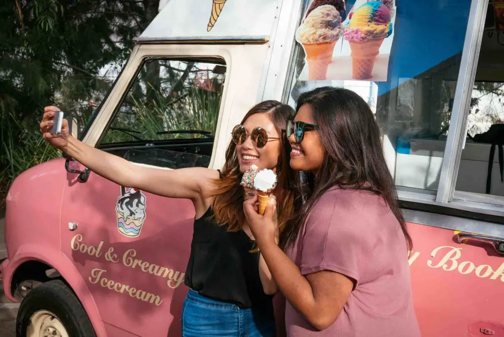 2 girls taking selfie in front of ice cream truck